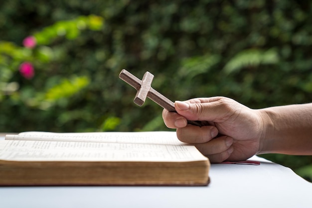 Man met een houten religieus kruis kruisbeeld met een open bijbel