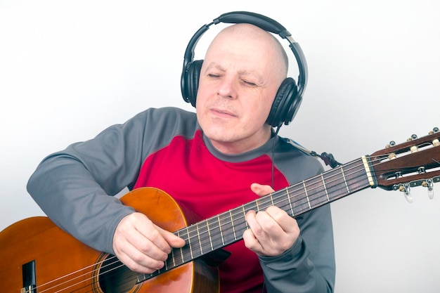 Man met een klassieke gitaar en koptelefoon op zijn hoofd, luisteren naar muziek