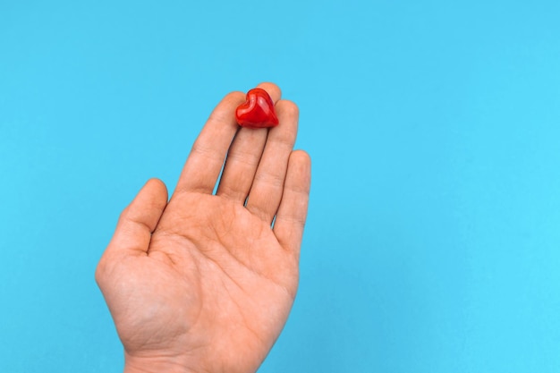 Man met een klein rood hart in de hand doneert en helpt concept achtergrond wereld hart en bloeddonor dag foto