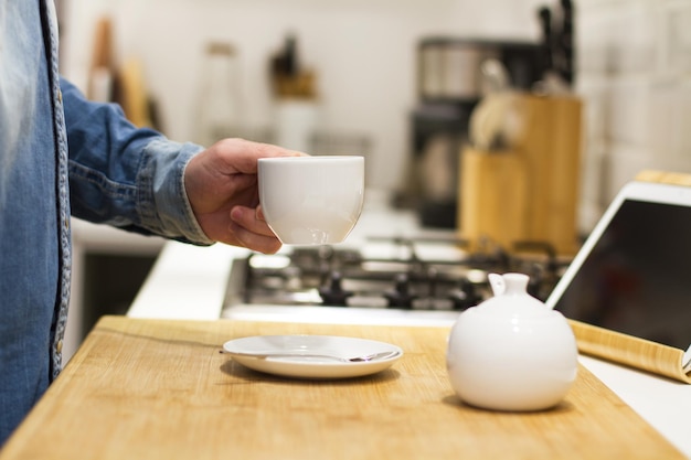 Man met een kopje koffie in zijn hand in de keuken