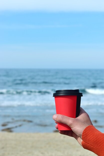 Man met een kopje koffie tegen de zee
