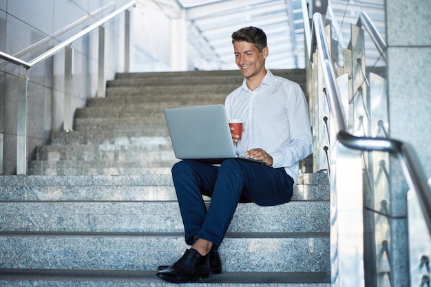 Man met een laptop zittend op de trap in een zakencentrum