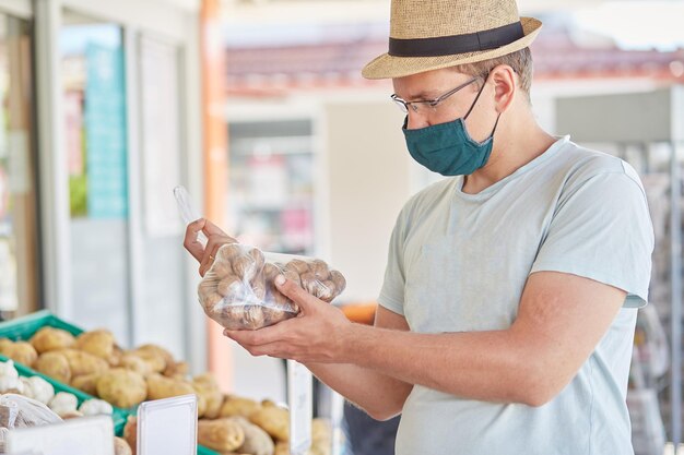 Man met een masker koopt groenten op een straatboer 39s markt Coronavirus quarantaineconcept Hoge kwaliteit foto