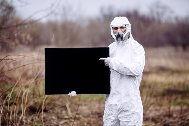 Foto man met een medisch masker en beschermend pak met een poster in zijn handen epidemie en medisch concept