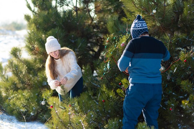 man met een meisje siert een groene kerstboom op een straat in de winter