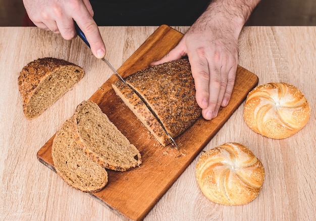 Foto man met een mes snijdt brood op een houten bord