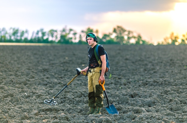 Man met een metaaldetector in het veld. Zoeken naar schatten.