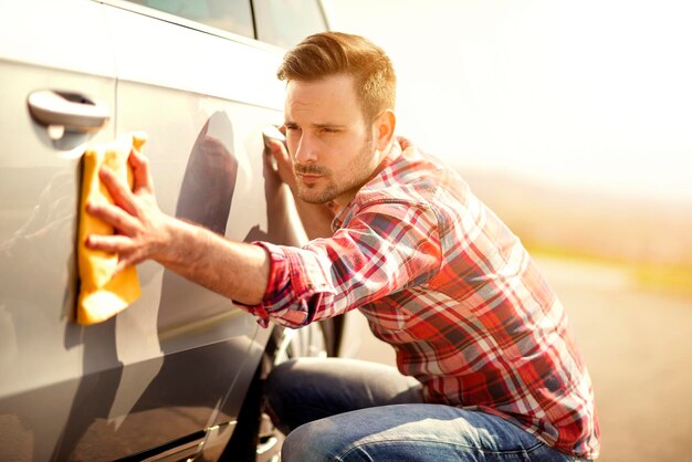 Man met een microvezel veegt de auto af met poetsen