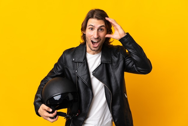 Man met een motorhelm geïsoleerd op geel met verrassing expressie