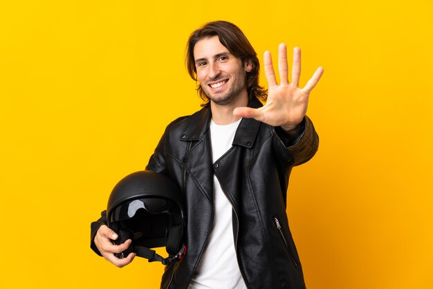 Man met een motorhelm geïsoleerd op geel vijf tellen met vingers