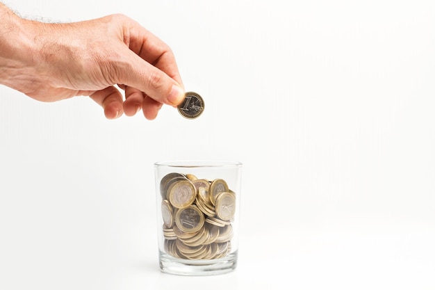 Man met een munt van 1 euro op een glas vol munten