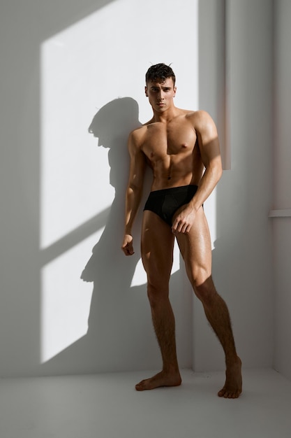 Man met een naakt opgepompt lichaam in zwarte onderbroek poseert op een foto van hoge kwaliteit