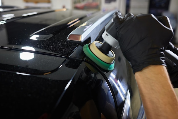 Man met een orbital polisher in auto werkplaats polijsten auto close-up