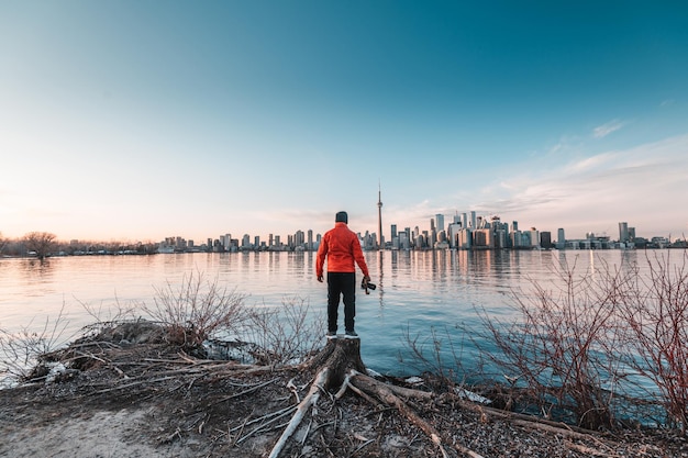 Man met een rood jasje met uitzicht op de skyline van Toronto in Ontario, Canada