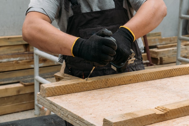 Man met een schroevendraaier tijdens het werken met houten materialen op een bouwplaats