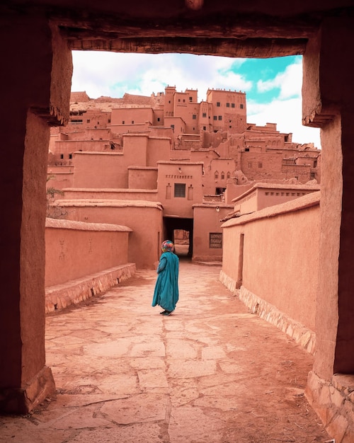 Man met een traditionele blauwe dooi op de achtergrond van Ait Benhaddou versterkte dorpsgebouwen