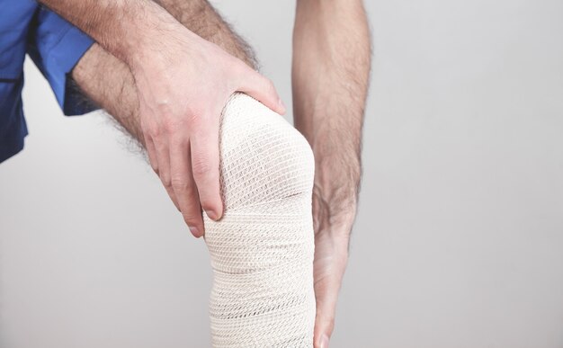 Man met een verband om zijn gewonde knie.