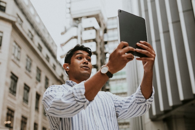 Man met een videogesprek op zijn digitale tablet in een stad