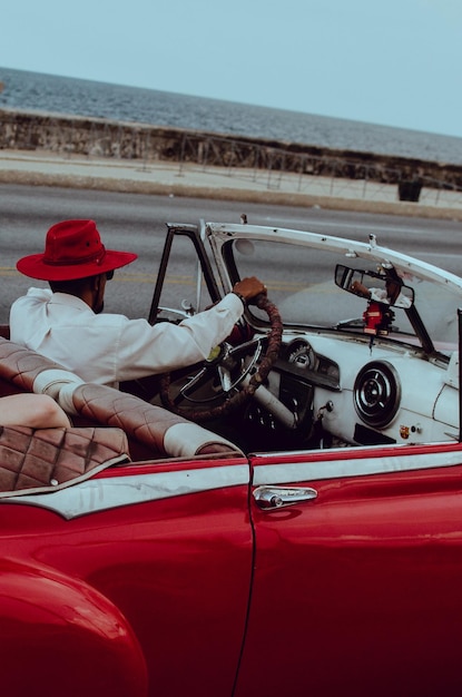 Foto man met een vintage auto tegen de zee