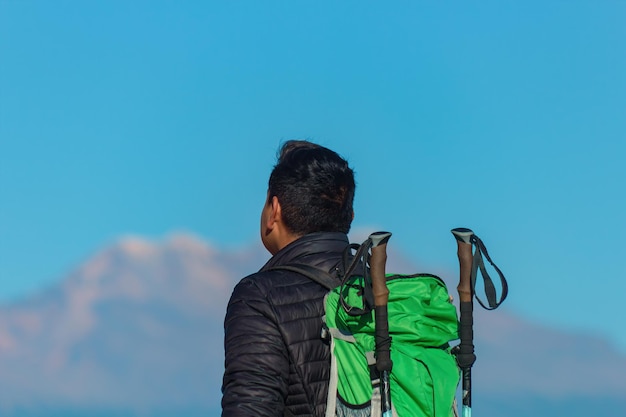 Man met felgekleurde kleding die uitkijkt op schilderachtige bergen