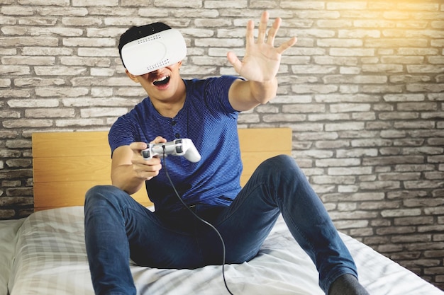 Foto man met gebaren tijdens het spelen van een videospel met een virtual reality simulator op bed