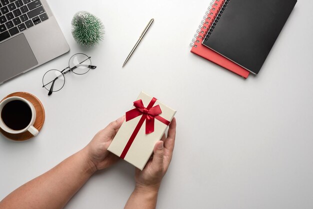 Man met geschenkdoos op een wit bureau. Kerstmis of Nieuwjaar cadeau geven concept.