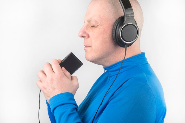 Man met gesloten ogen luistert naar muziek met een koptelefoon op een lichte achtergrond
