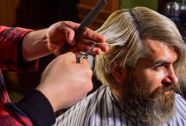 Man met geverfd haar Kapper kapsel kapperszaak Hipster wordt geknipt Professionele cosmetica Schaar knippen Kort haar is niet altijd minder werk dan lang haar Donatie en liefdadigheidsconcept