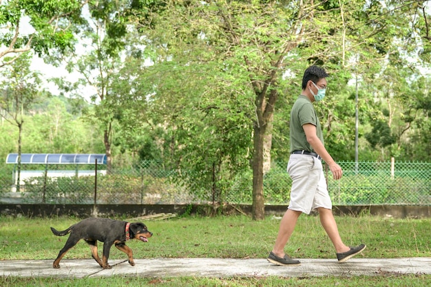 Man met gezichtsmasker wandelen met hond in het park