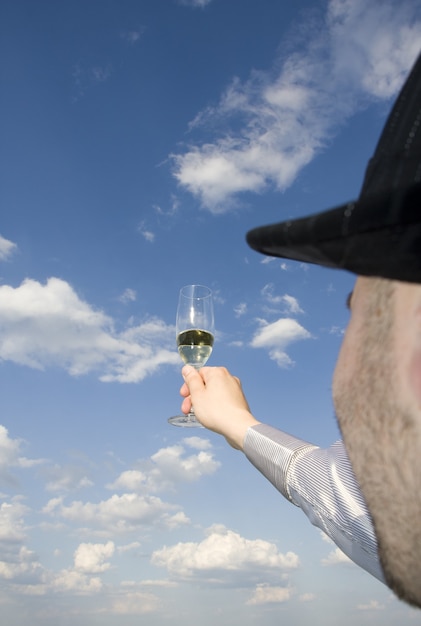 Man met glas wijn in bewolkte hemel