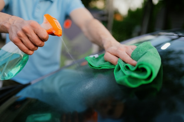 Man met glazenwasser en een doek, auto wassen met de hand