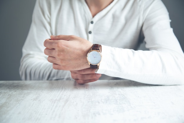 Man met hand op zijn horloge op bureau