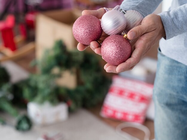 Man met handvol rose goud en zilver glitter kerstballen.