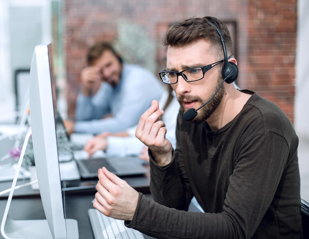 Foto man met headset zit bij computers in een licht kantoor