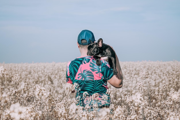 Man met hond die bij bloeiende bloemen staat