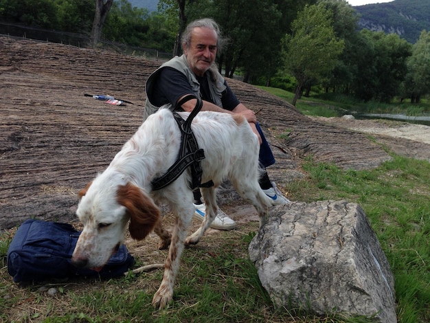 Foto man met hond die op het veld zit