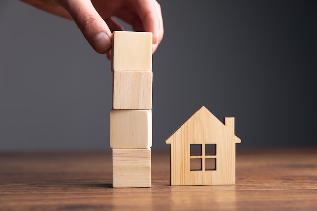 Man met houten kubussen en huismodel op tafel