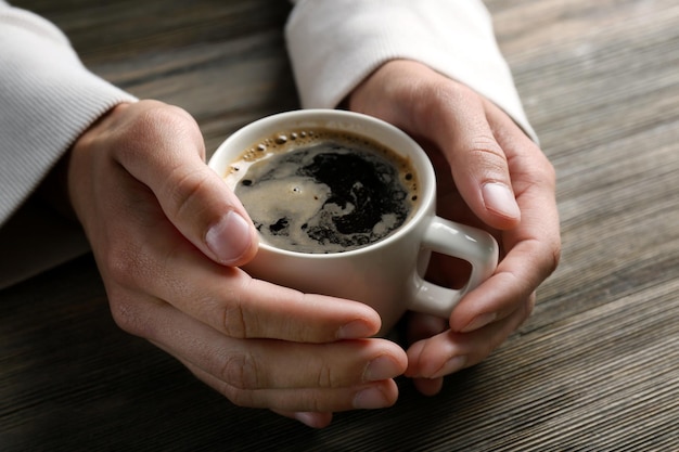 Man met in handen kopje koffie op houten achtergrond