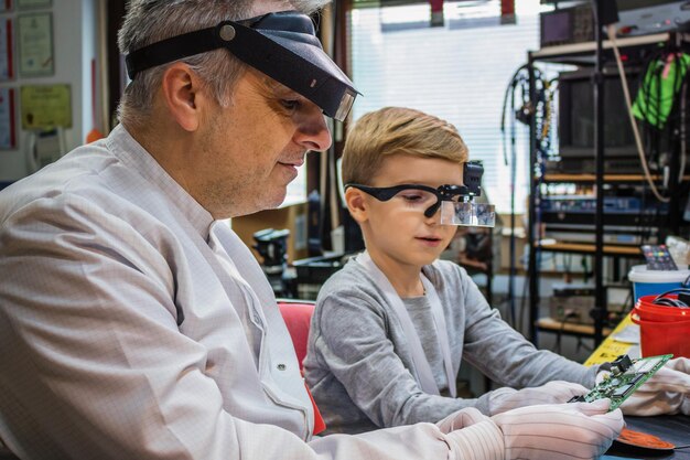 Foto man met jongen die een computeronderdeel onderzoekt