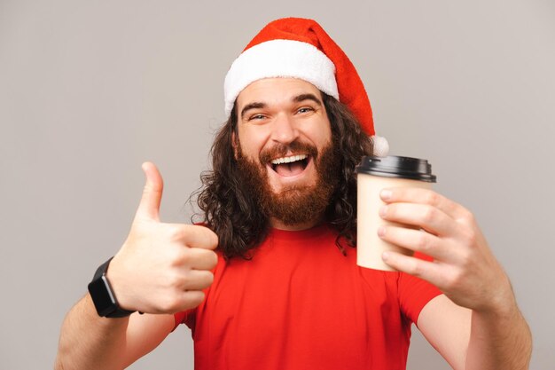 Man met kerstmuts beveelt met een duim omhoog deze afhaalkoffie aan