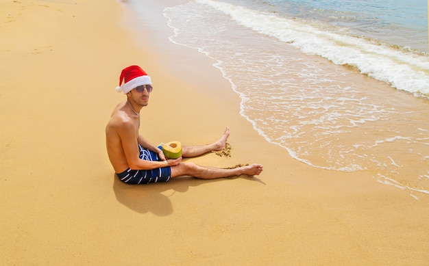 Man met kerstmuts op het strand