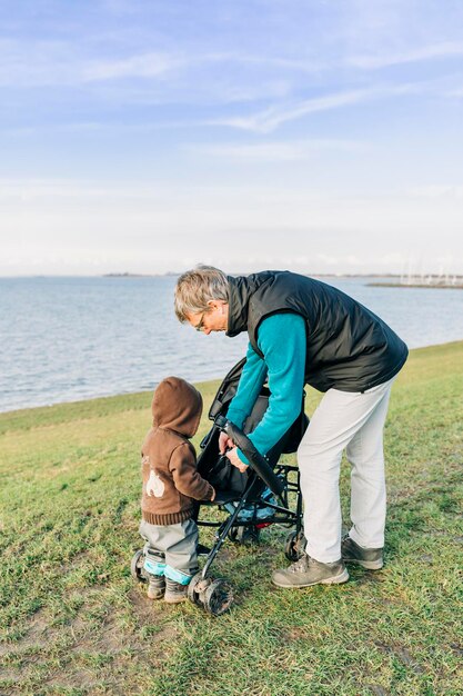 Man met kleindochter op de grasrijke oever van het meer tegen de blauwe lucht