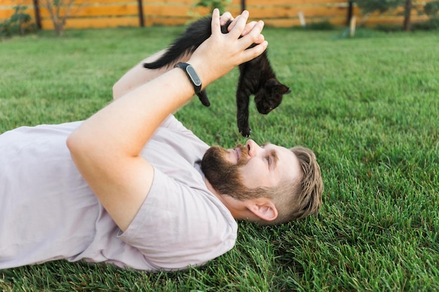 Man met kleine kitten liggend en spelend op gras vriendschap liefde dieren en huisdier eigenaar concept