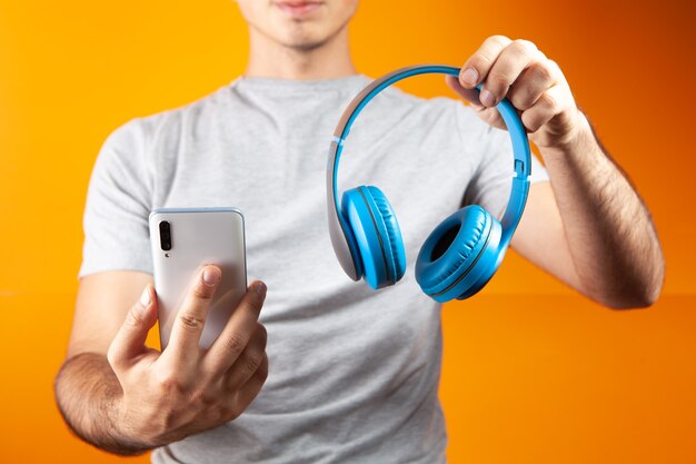 Man met koptelefoon en telefoon op oranje achtergrond