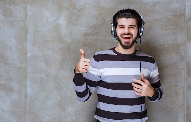 Man met koptelefoon luisteren naar de muziek en tevredenheidsteken tonen