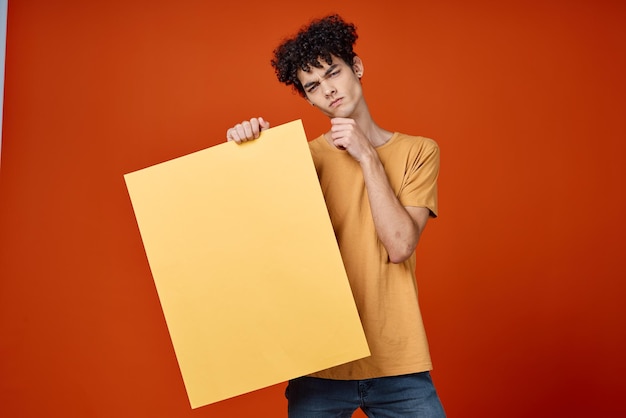 Man met krullend haar gele poster in handen studio kopie advertentieruimte