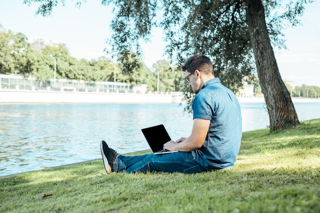 Man met laptop buiten zitten in de natuur