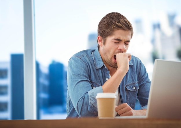 Man met laptop en koffie tegen wazige blauwe skyline