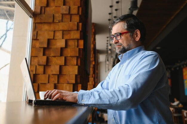 Man met laptop in café-bar