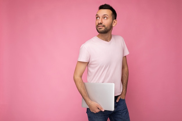 man met laptop opzoeken in t-shirt op geïsoleerde roze